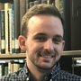 portrait of Jonathan standing in front of bookshelf