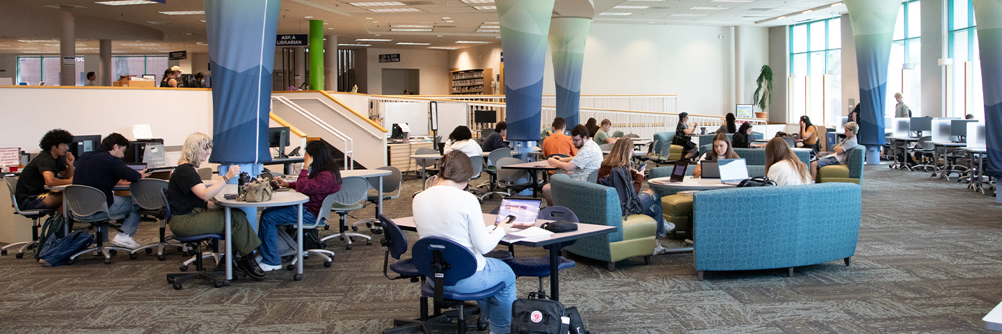 Picture of students sitting around the tables in the Cannell library studying .
