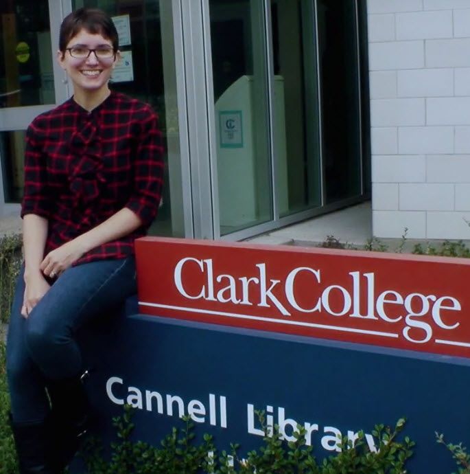 smiling woman sits on Cannell Library sign near the library's front door
