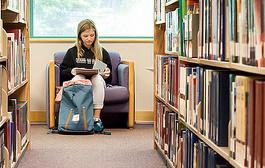 young woman reading by bookshelves